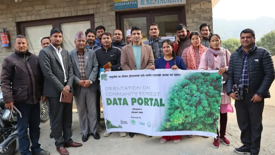 A group of participants outside a building holding a banner reading Orientation on Community Forest Data Portal.